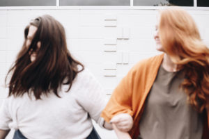 two women hooking arms and walking